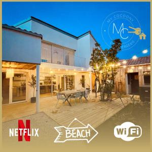 a house with a deck with a table in front of it at La Petite Cabine, 3chambres proche plage et centre in Les Sables-dʼOlonne