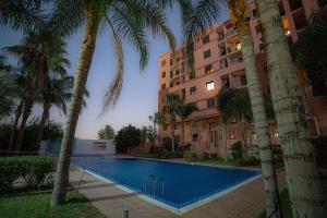 une piscine devant un immeuble avec des palmiers dans l'établissement œil de la vallée, à Marrakech