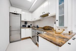 a kitchen with white cabinets and a wooden counter top at CB Living - Cozy condo with patio, Playa Flamenca in Orihuela Costa +24 photos