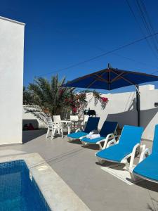 a group of blue lounge chairs and a swimming pool at Villa Aline Lagune Djerba in Midoun