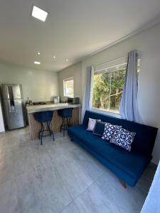 a living room with a blue couch and a kitchen at Greek House Premium in Arraial do Cabo