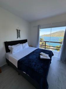 a bedroom with a bed with a view of the ocean at Greek House Premium in Arraial do Cabo