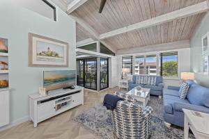 Una sala de estar con un sofá azul y un televisor. en Island Retreat Loggerhead Cay 443, en Sanibel