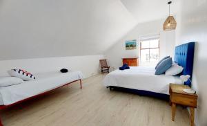 a bedroom with two beds and a chair in it at 8 Eden Villa in Yzerfontein