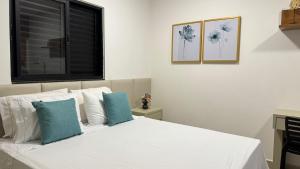 1 dormitorio con 1 cama blanca y 2 almohadas azules en 107-4 · Suíte Aconchego Blue prox. UniEvangélica, en Anápolis