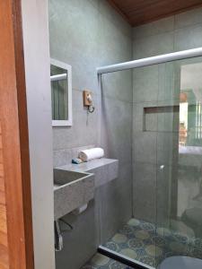 a bathroom with a shower with a sink and a glass shower at Jardim UIXA in Ilha de Boipeba