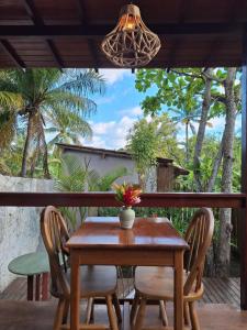 a wooden table and chairs on a porch with a view at Jardim UIXA in Ilha de Boipeba