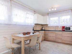 a kitchen with white cabinets and a wooden table and chairs at Cottage in Pobierowo near Baltic Beach in Pobierowo +21 photos
