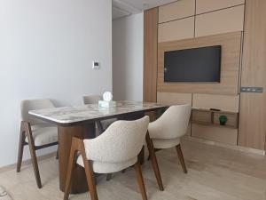 jadalnia ze stołem i krzesłami oraz telewizorem w obiekcie Élégant appartement moderne au cœur d Agadir Bay w mieście Agadir