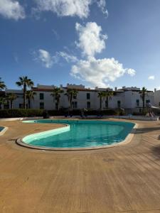 a swimming pool with palm trees and a building at Vila Verde TownHouse T53 by RPG Group in Santa Maria