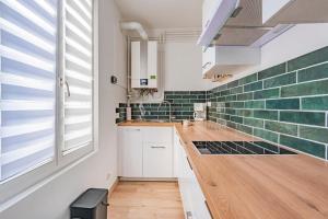 a kitchen with white cabinets and green subway tiles at El verde in Épernay