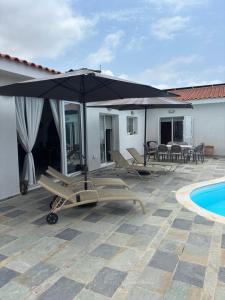 a patio with an umbrella and chairs next to a pool at Sunset Bungalow in Paphos City