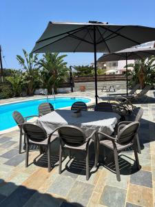 a table and chairs with an umbrella next to a pool at Sunset Bungalow in Paphos City