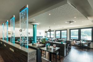 un restaurante con mesas, sillas y ventanas en Rheinterrassen Hotel Café Restaurant, en Widdig