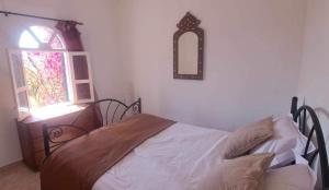 - une chambre avec un lit, une fenêtre et un miroir dans l'établissement Riad Diaz Taghazout, à Ikouzza