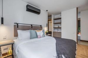 Un dormitorio con una gran cama blanca con almohadas. en Morph 501 - Spacious Cozy Apt Poblado/BBQ/Jacuzzi, en El Poblado 38 fotos más