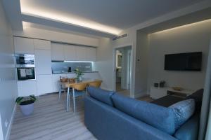 a living room with a blue couch and a kitchen at Rosa Garden Retreat in São Roque