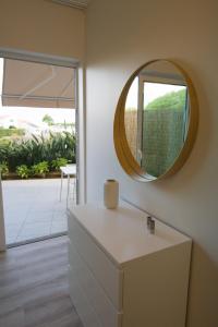 een spiegel aan een muur in een kamer met een dressoir bij Rosa Garden Retreat in São Roque