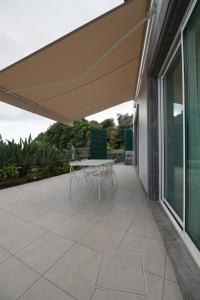 een terras met een tafel en stoelen onder een luifel bij Rosa Garden Retreat in São Roque
