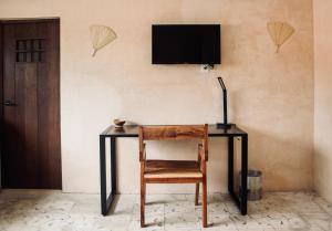 a desk with a chair and a television on a wall at Hotel Casa Nudo, Chukum, Mérida in Mérida