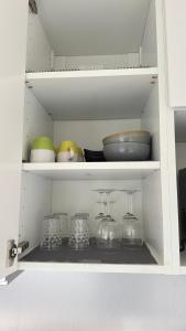 a cabinet filled with bowls and other dishes at Studio cosy aux portes de Geneve in Ferney-Voltaire