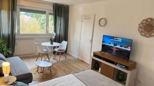 a living room with a couch and a tv and a table at Studio cosy aux portes de Geneve in Ferney-Voltaire
