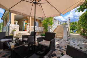 a patio with chairs and a table with an umbrella at Apartments Mig in Supetarska Draga