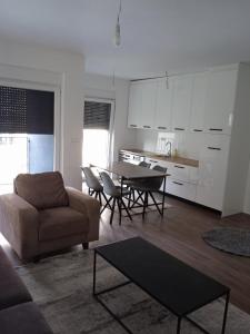 a living room with a table and chairs and a kitchen at Pristhine Stay Inn 21 in Prishtinë
