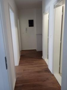 an empty hallway with white walls and wood floors at Pristhine Stay Inn 21 in Prishtinë