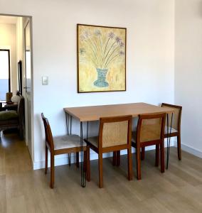 a dining room table with chairs and a painting on the wall at apartamento confort in Balneário Camboriú