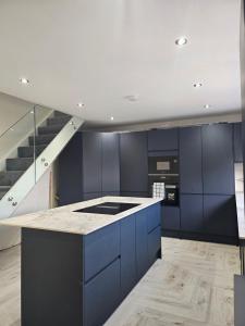 eine Küche mit blauen Schränken und einer Treppe in der Unterkunft Luxury 3 bed next to city centre in Killingbeck