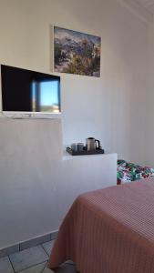 a bedroom with a bed and a flat screen tv at Le Rose Antiche in Murta Maria