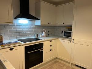 una cucina con mobili bianchi e un forno a piano cottura di Warrington House - Sleeps 6 - WiFi - Free Parking - Contractor Friendly a Warrington
