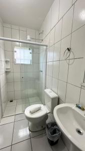 a white bathroom with a toilet and a sink at Pousada Suíte Verde Mar in Ubatuba