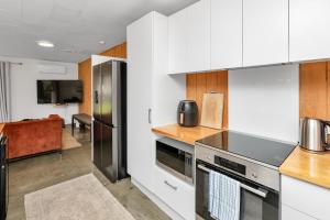 a kitchen with white cabinets and stainless steel appliances at Ruakaka Coastal Reserve Retreat in Ruakaka