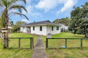 a white house with a fence in front of it at Ruakaka Coastal Reserve Retreat in Ruakaka