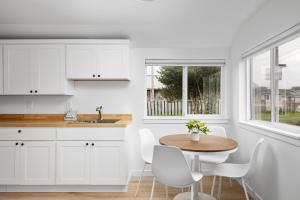 a kitchen with white cabinets and a wooden table and chairs at Inn at Rockaway Beach Unit #5 in Rockaway Beach +5 photos