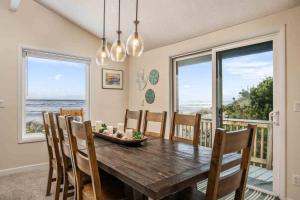 a dining room with a table and chairs and windows at Beachfront Family Sanctuary in Rockaway Beach
