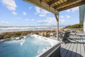 a hot tub on a deck next to the beach at Beachfront Family Sanctuary in Rockaway Beach