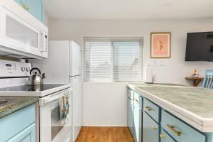 a kitchen with blue cabinets and a white refrigerator at Sea Haven Motel Unit .7 in Rockaway Beach +13 photos