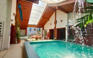 a swimming pool in a house with a fountain at Hotel Casa Branca in Guarujá