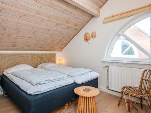 a bedroom with a bed and a window and a table at 6 person holiday home in Rømø in Sønderby