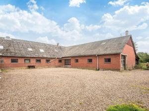 a large red brick barn with a gravel driveway at 6 person holiday home in Gram in Gram