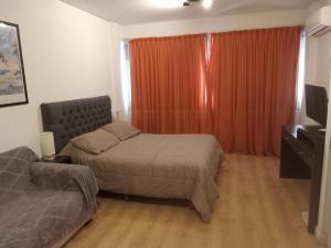 1 dormitorio con 2 camas y una ventana con cortina naranja en Oro Plaza Apartamentos, en Buenos Aires