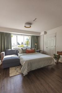 ノースバンクーバーにあるModern Lynn Valley Retreat with Mountain and City Viewsの大きなベッドとソファのある寝室