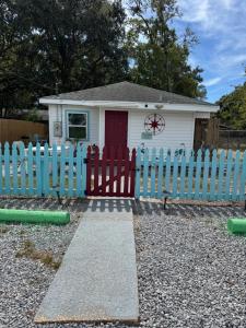 a white house with a blue picket fence at Blue Heron cottage in Gulfport