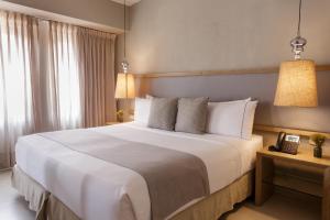 a bedroom with a large white bed and a telephone at Hotel Santa Cecilia B&B in Cartagena de Indias