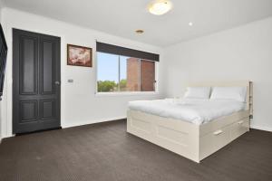 Un dormitorio blanco con una cama y una ventana. en Your Home Retreat in Maribyrnong, en Melbourne
