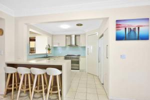 Una cocina con gabinetes blancos y una encimera con taburetes. en Your Home Retreat in Maribyrnong, en Melbourne 9 fotos más