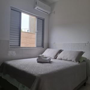 a white bedroom with a large bed with a window at Residencial Caramujo in Florianópolis